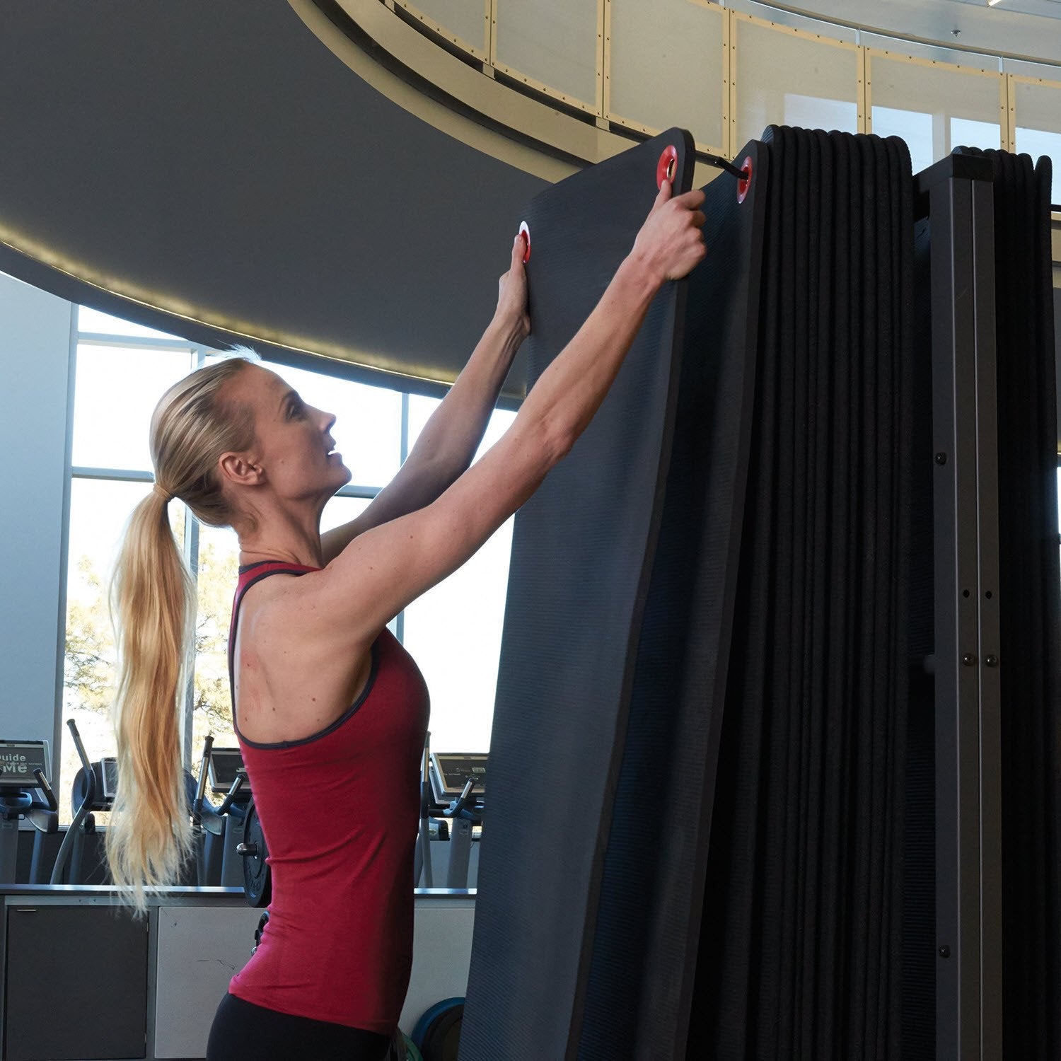 Woman hanging mats on the Wall-Mounted Mat Rack